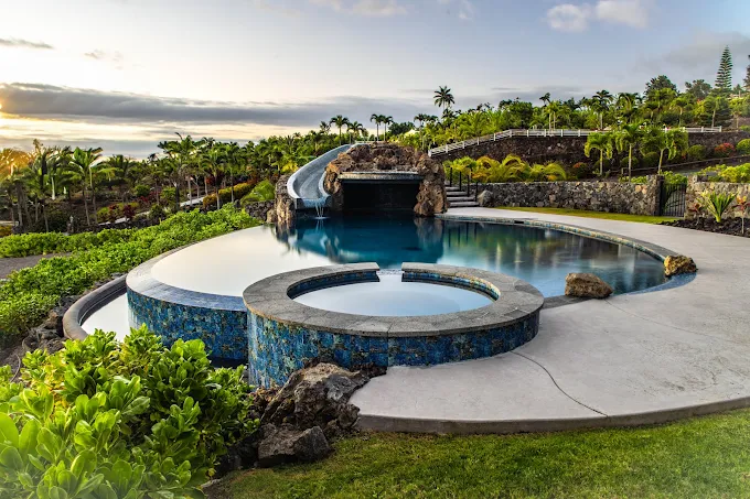 Custom island pool with a raised circular spa and waterslide